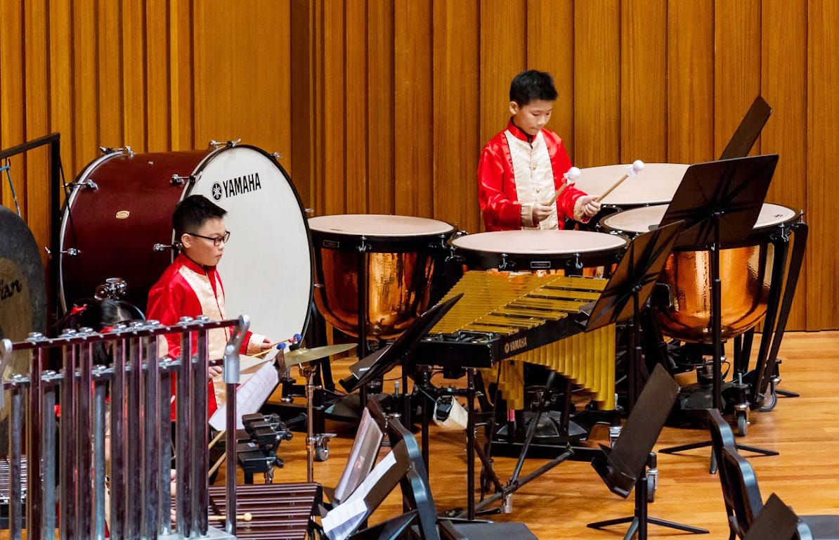 Students perform on percussion instruments during a concert, showcasing rhythm, coordination and musical teamwork.
